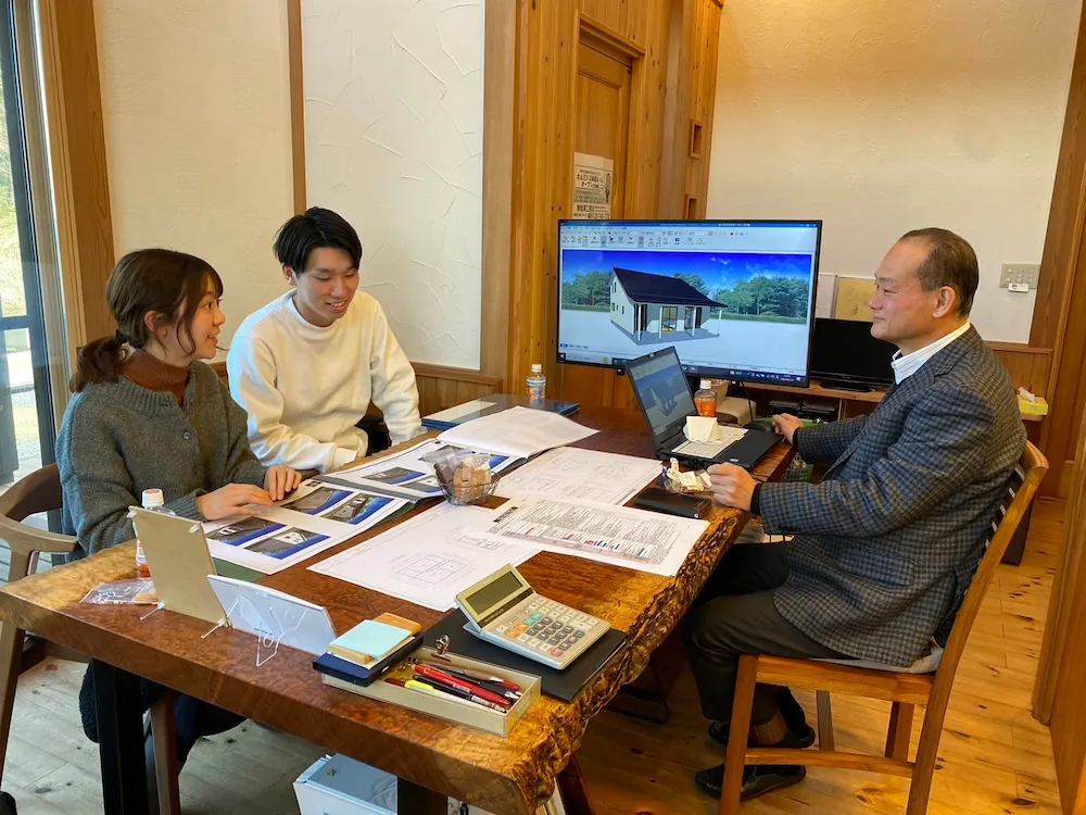 外観パースを見ながら初回相談するご夫婦と代表