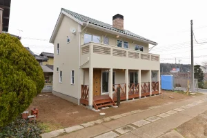 薪ストーブと壁一面の本棚。柱の並ぶポーチが迎えるカントリーハウス