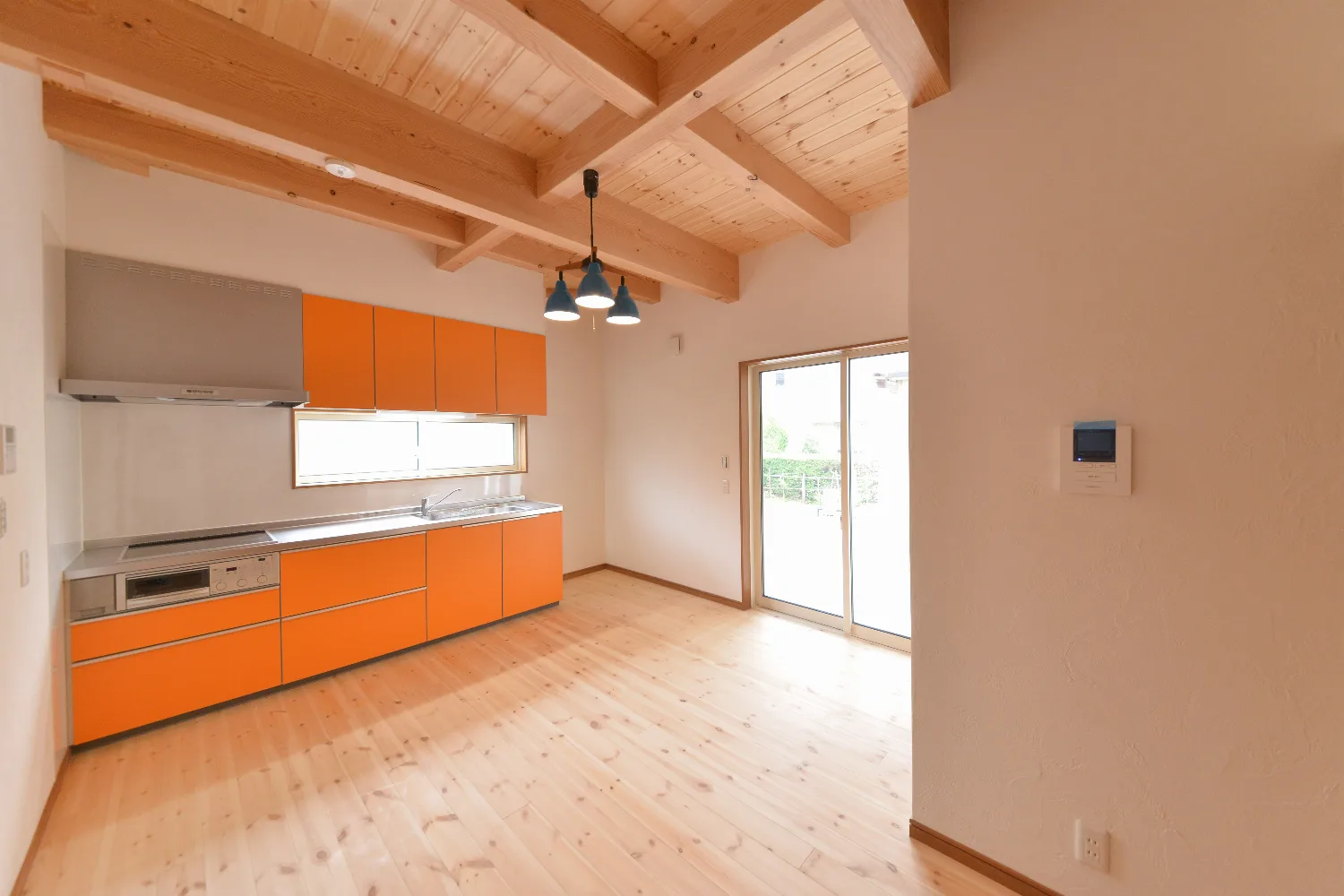 太い梁とオレンジのキッチン。和室が並ぶ、大屋根の家