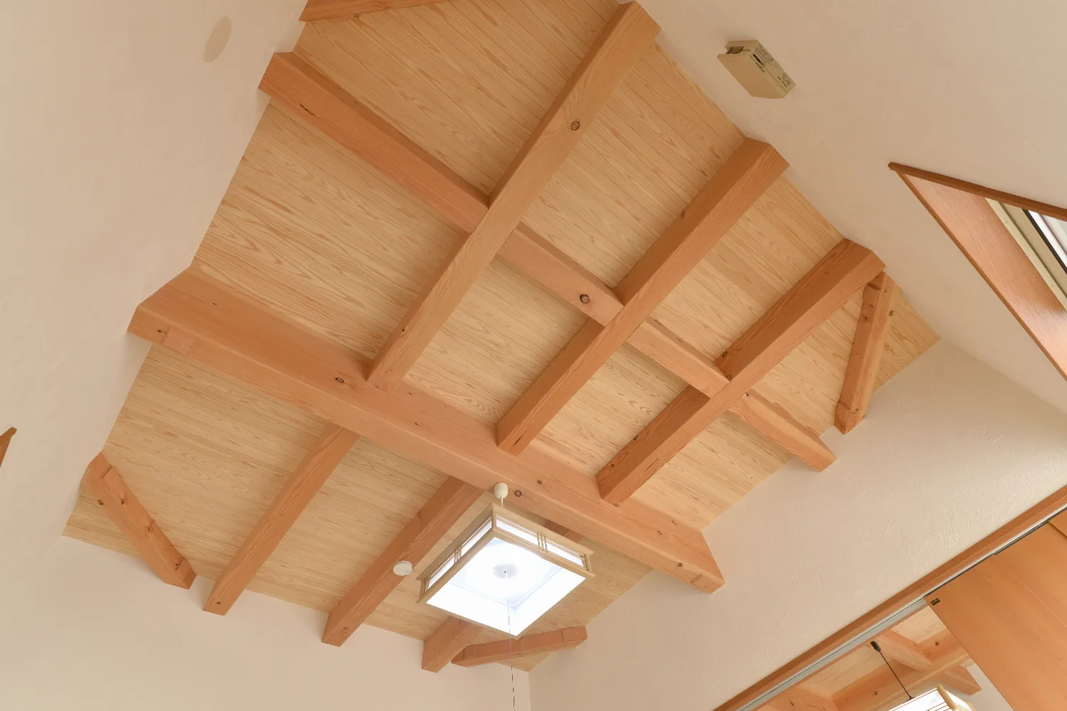 太い梁とオレンジのキッチン。和室が並ぶ、大屋根の家