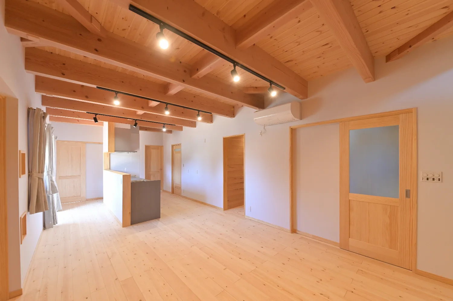 登り梁を見上げる平屋。ウッドデッキと太陽光を備えた住まい